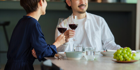 モダンなリビングダイニングで赤ワインを飲む夫婦