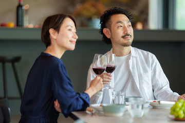 モダンなリビングダイニングで赤ワインを飲む夫婦