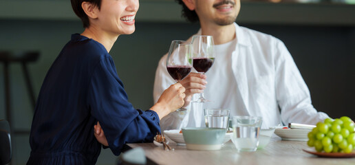 モダンなリビングダイニングで赤ワインを飲む夫婦