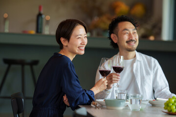 モダンなリビングダイニングで赤ワインを飲む夫婦