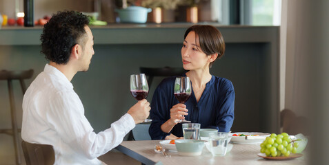 モダンなリビングダイニングで赤ワインを飲む夫婦