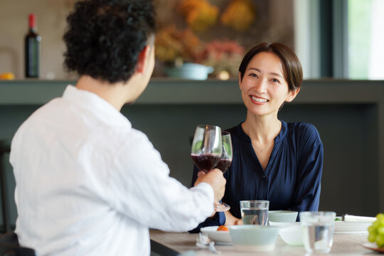 モダンなリビングダイニングで赤ワインを飲む夫婦