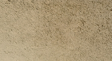 Detailed beige stucco wall texture fills the frame, showcasing a rough, uneven surface with shadows enhancing depth and tactile quality, creating a warm, earthy feel under soft light.