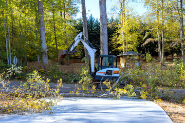 Heavy machinery removes debris from road surrounded by trees after hurricane in fall season.