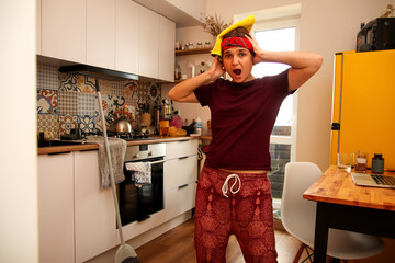 fun image of a Gen Z hipster woman in a dirty kitchen, with a look of surprise or scared on her...