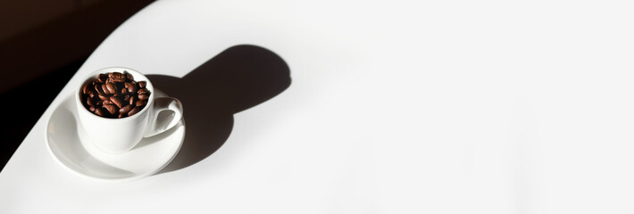 minimal mock up with a clean white background and a full cup of coffee beans. a shadow of a coffee bean and plenty of copy space