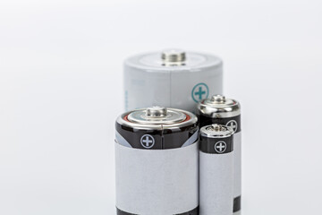 Various size batteries with metallic tops and white labels, arranged on white background, showing...