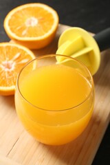 Fresh orange juice in glass, fruits and juicer on table, closeup