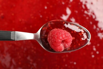 Delicious raspberry jam and spoon with berry as background, top view