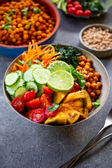 Buddha bowl - vegetarian bowl with chickpeas and fresh vegetables on the grey table vertical photo