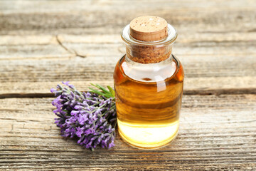 Lavender essential oil and flowers on wooden table, closeup