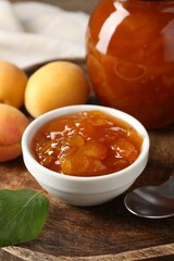 Tasty apricot jam and fresh fruits on wooden table, closeup