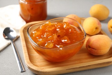 Tasty apricot jam and fresh fruits on light grey table, closeup