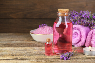 Lavender essential oil, flowers, candle, sea salt and towels on wooden table. Space for text