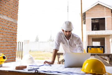 Hispanic male engineer working : Architect and contractor worker planning and architecture working in house building under construction site. Engineering in safety harthat helmet