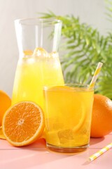 Refreshing soda water with orange slice in glass, jug and fresh fruits on pink wooden table, closeup