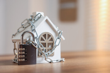 Home security. House model with chain and padlock on wooden table indoors, space for text
