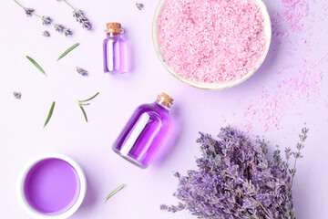 Obraz na płótnie Canvas Aromatic essential oil, sea salt and lavender flowers on violet background, flat lay