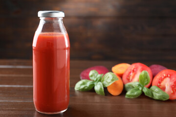 Tasty juice in glass bottle, fresh vegetables and basil on wooden table, selective focus