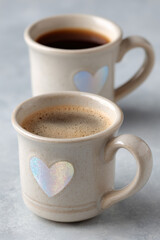 pair of coffee mugs with holographic heart designs on clean white background