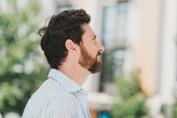 Naklejka premium Side profile of a stylish young man outside in an urban setting during a sunny day showcasing modern lifestyle