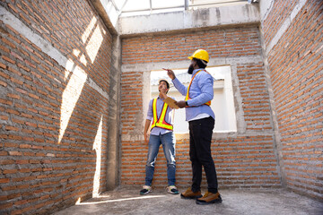 interior design : Architects and contractor working together inside building under construction site. home renovation process. Engineering in safety harthat helmet. Engineering team