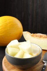 Cut and whole ripe melons on black wooden table, closeup