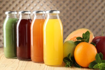 Tasty juices in glass bottles, fresh ingredients and mint on wooden table indoors, closeup