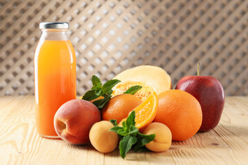 Tasty juice in glass bottle, fresh fruits and mint on wooden table indoors, closeup
