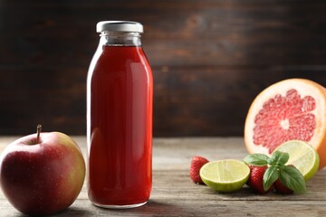 Tasty juice in glass bottle, fresh ingredients and basil on wooden table against brown background, closeup