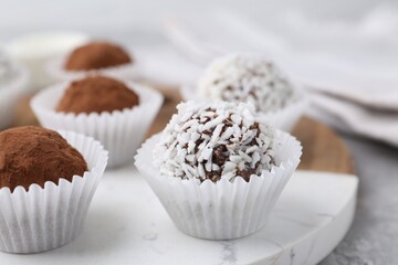 Delicious homemade candies with cocoa powder and coconut flakes on table, closeup