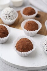 Delicious homemade candies with cocoa powder and coconut flakes on table, closeup