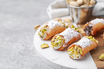 Delicious cannoli with ricotta cheese, pistachios and powdered sugar on grey marble table, closeup. Space for text