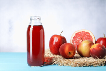 Tasty juice in glass bottle and fresh fruits on light blue wooden table