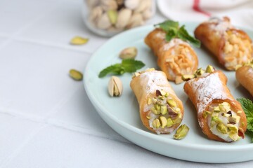 Delicious cannoli with cheese, nuts and mint on white table, closeup. Space for text
