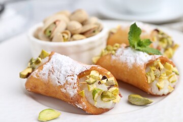Delicious cannoli with cheese, pistachios, powdered sugar and mint on table, closeup