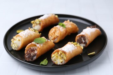 Delicious cannoli with cheese, nuts, powdered sugar, chocolate and mint on white table, closeup