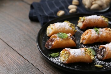 Delicious cannoli with cheese, nuts, powdered sugar, chocolate and mint on wooden table, closeup....