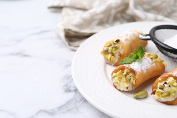 Delicious cannoli with cheese, pistachios, powdered sugar and mint on white marble table, closeup. Space for text