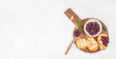 Toasted bread with caramelized red onion spread served on a wooden board. Long banner format. top view. copy space