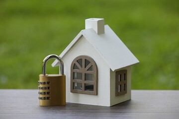 Home security. House model and padlock on wooden table outdoors, closeup