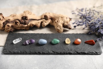 Chakra gemstones and lavender flowers on light table, closeup