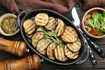 Grilled slices of eggplant with microgreens served on wooden table, flat lay
