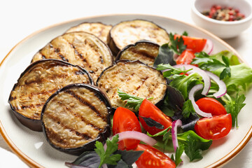 Grilled slices of eggplant with salad on white table, closeup