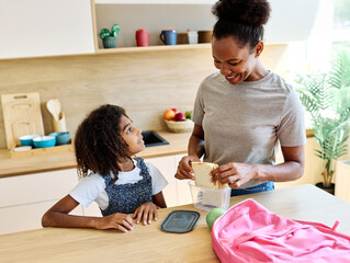 Mother helping daughter to get ready for school, helping her with backpack and books, and making snack sandwich in the kitchen hugging and leaving home