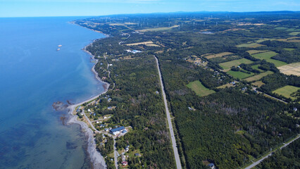 Obraz premium Panoramic aerial view demonstrating the aesthetic impact of a wind farm on a rural coastal landscape along the St. Lawrence River. Baie-des-Sables, Quebec, Canada, 2025.
