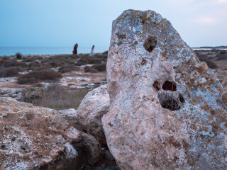 Closeup of a huge porous rock with big holes like paw footprints stand vertically on the shore of...