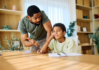 Fototapeta premium Father and son doing homework fighting and arguing over learning at home. Boy being bored looking through window, Father helping son with homework while showing concern for his frustration