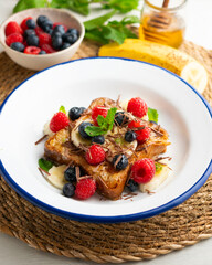 French toast cooked with butter and with red fruits and banana.