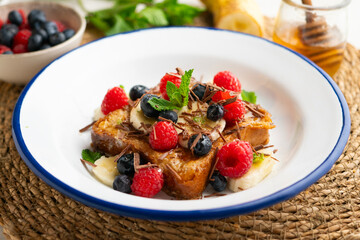 French toast cooked with butter and with red fruits and banana.